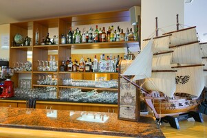 A bar area with shelves of liquor bottles and glasses, and a model ship on display.