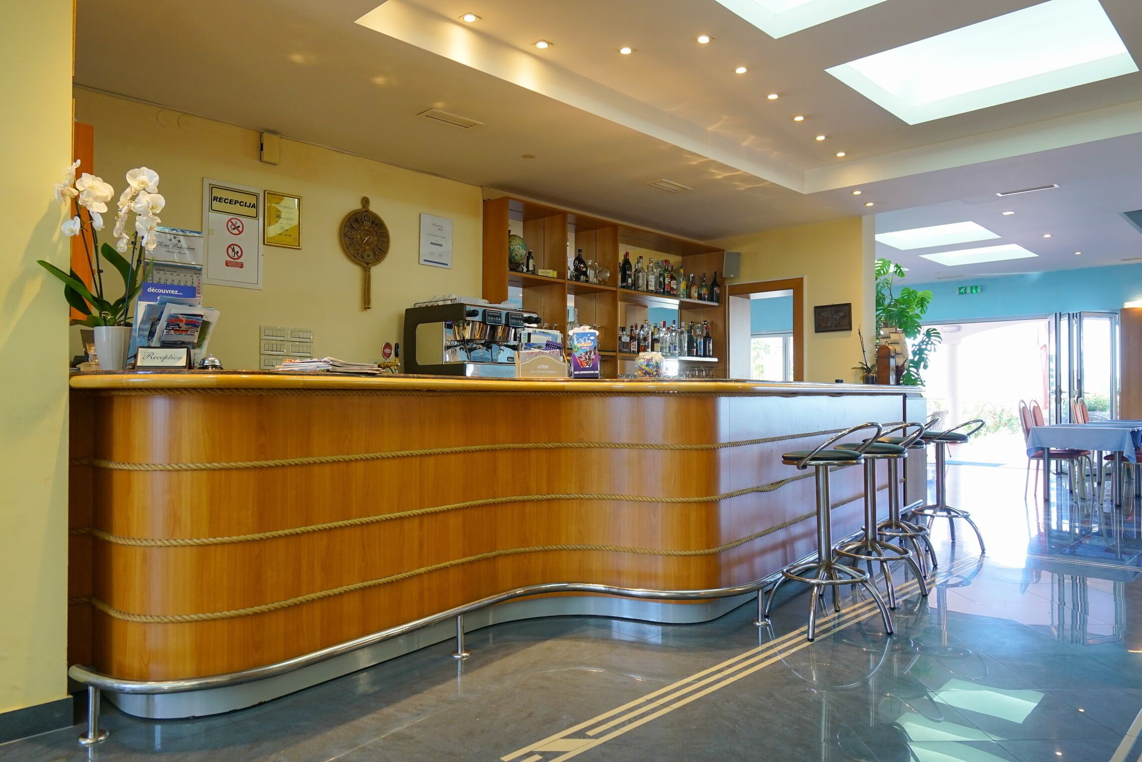 A reception area with a wooden counter, bar stools, a reception desk, and a wall-mounted clock.