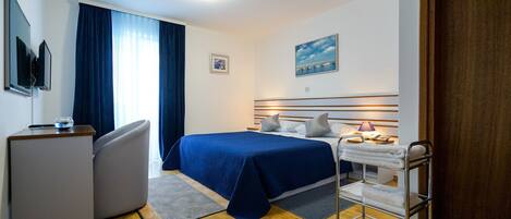 Ein Hotelzimmer mit Bett, Nachttisch, Lampe und Schreibtisch mit Stuhl.