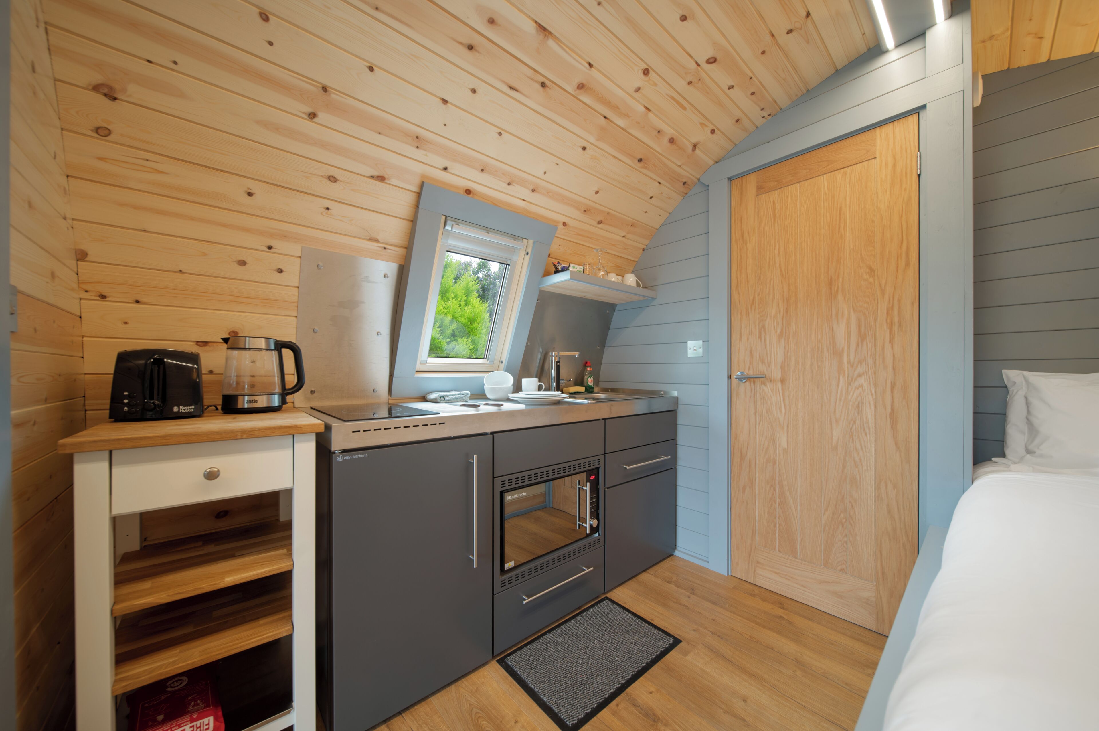 A compact kitchen with a built-in oven, a coffee maker, and a window.