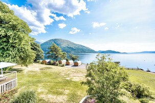 Una propiedad junto al lago con un área de césped, una terraza de madera y tres cabañas de madera.
