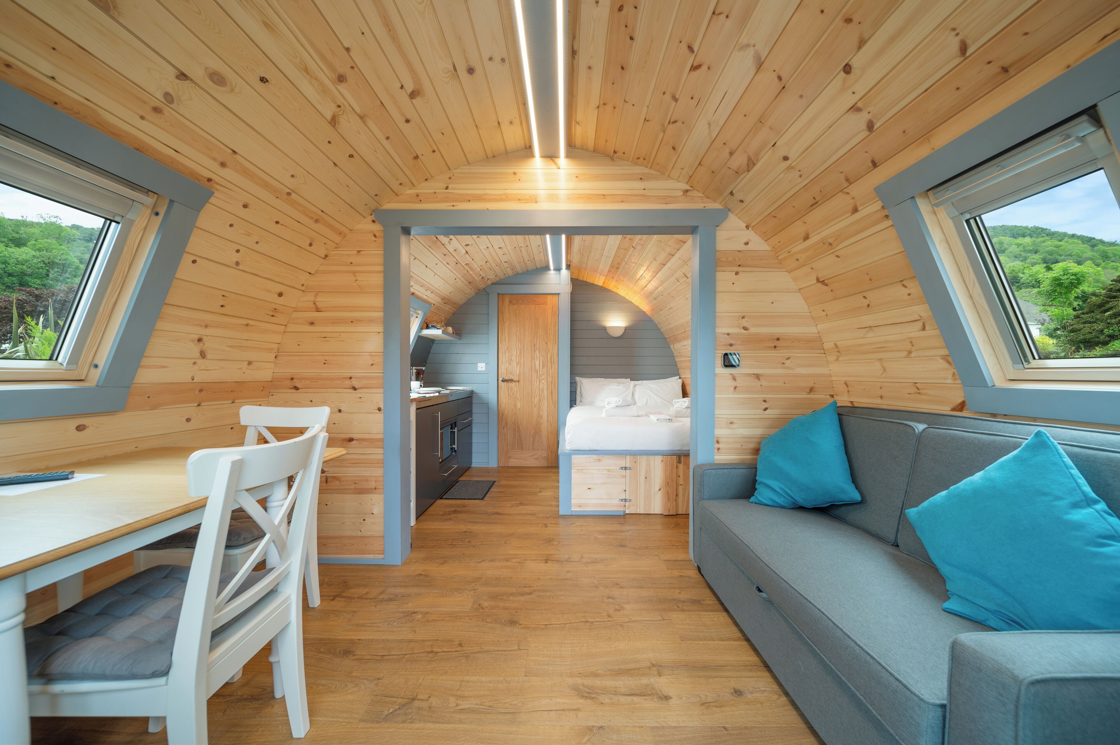 Un intérieur chaleureux avec des murs en bois, un coin repas, un canapé et un lit.