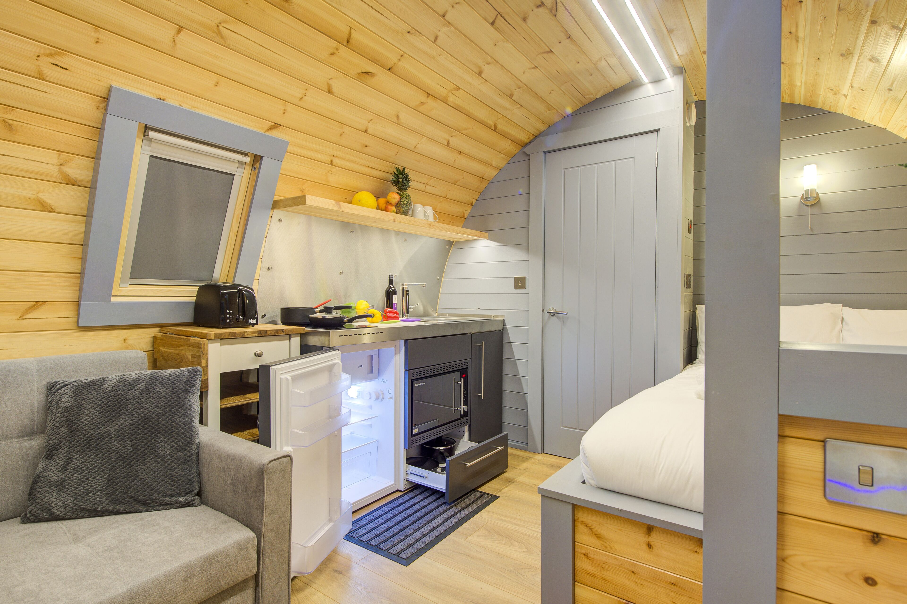 A compact room with a kitchenette, a bed, and a seating area.
