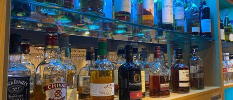 A bar with various bottles of alcohol, including whiskey and scotch, displayed on shelves.