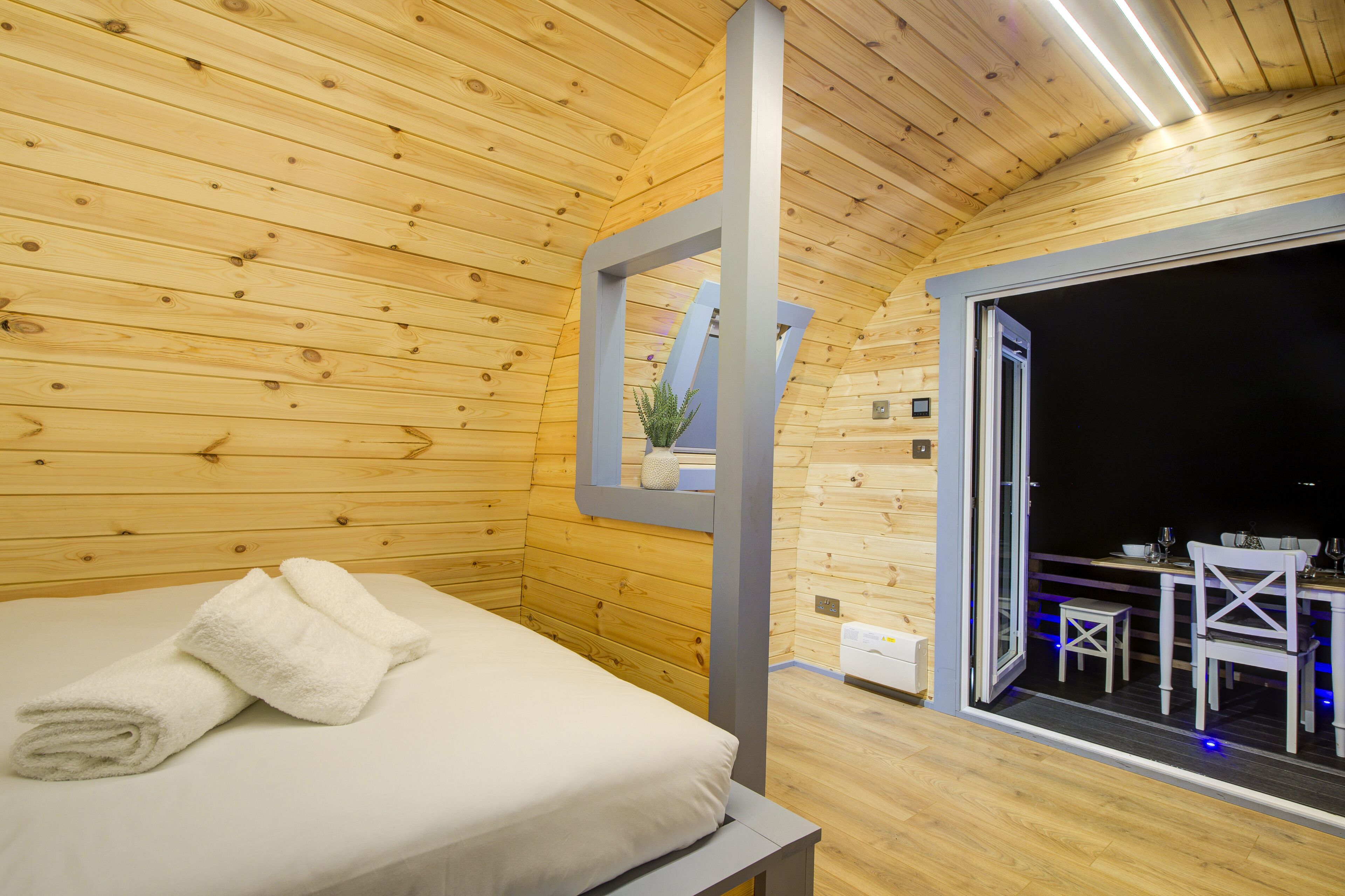 A wooden cabin room with a bed, a window, and a table with chairs.