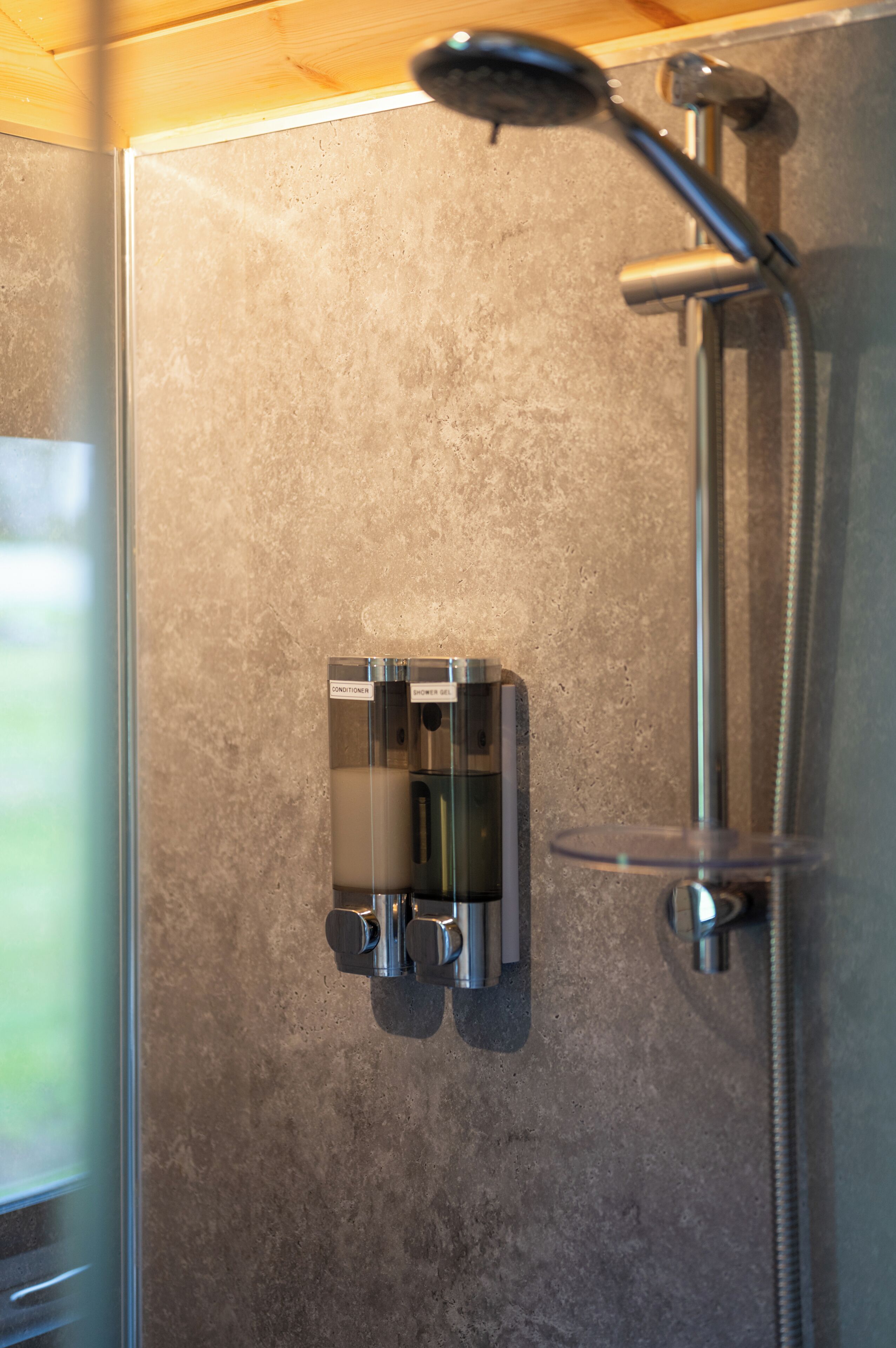 A shower with a handheld showerhead and a wall-mounted control panel.