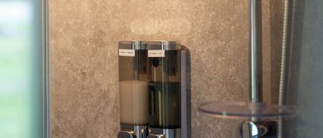 A shower with a handheld showerhead and a wall-mounted control panel.