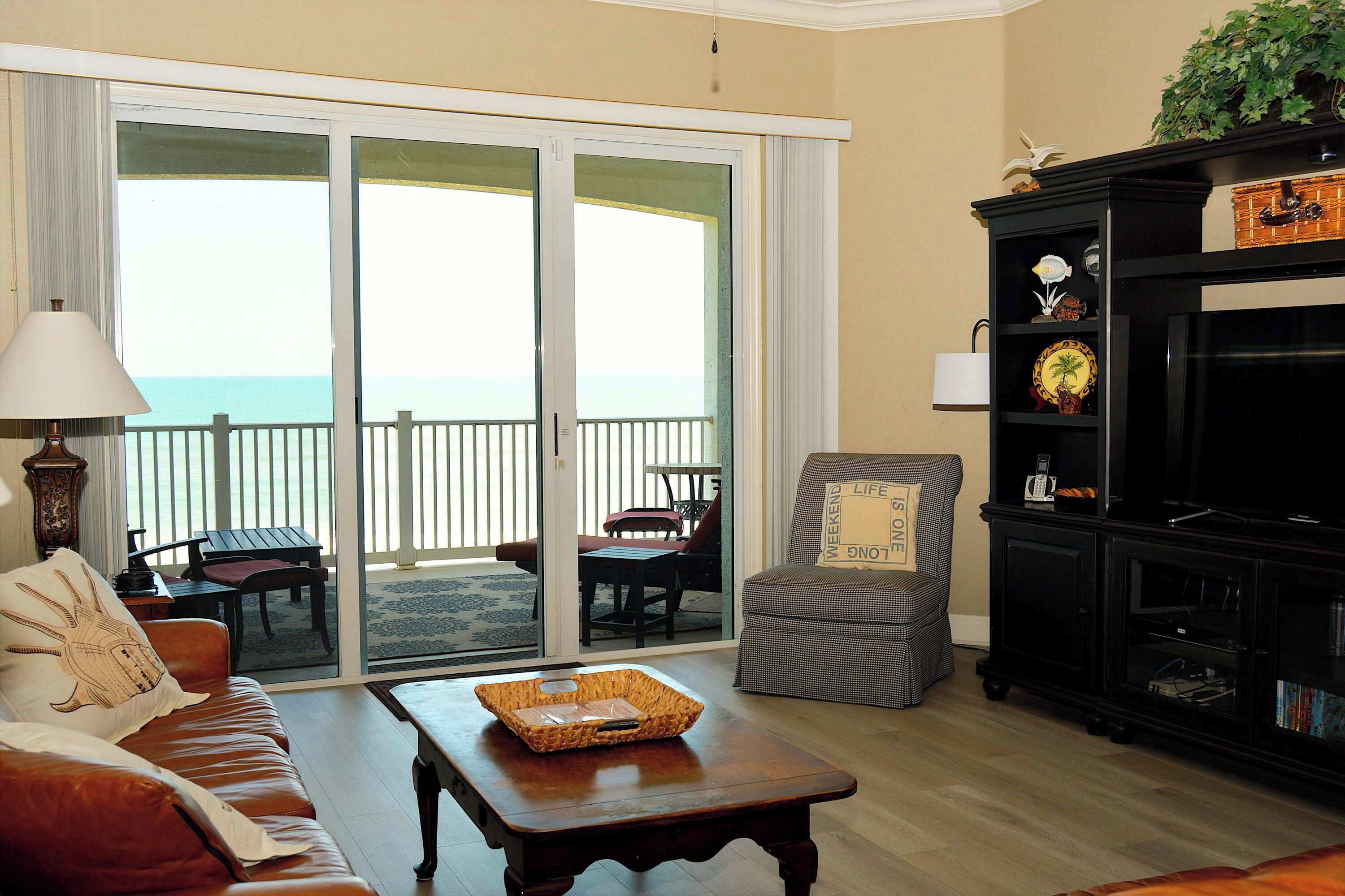 A living room with a sofa, a coffee table, a television, and a sliding glass door leading to a balcony.