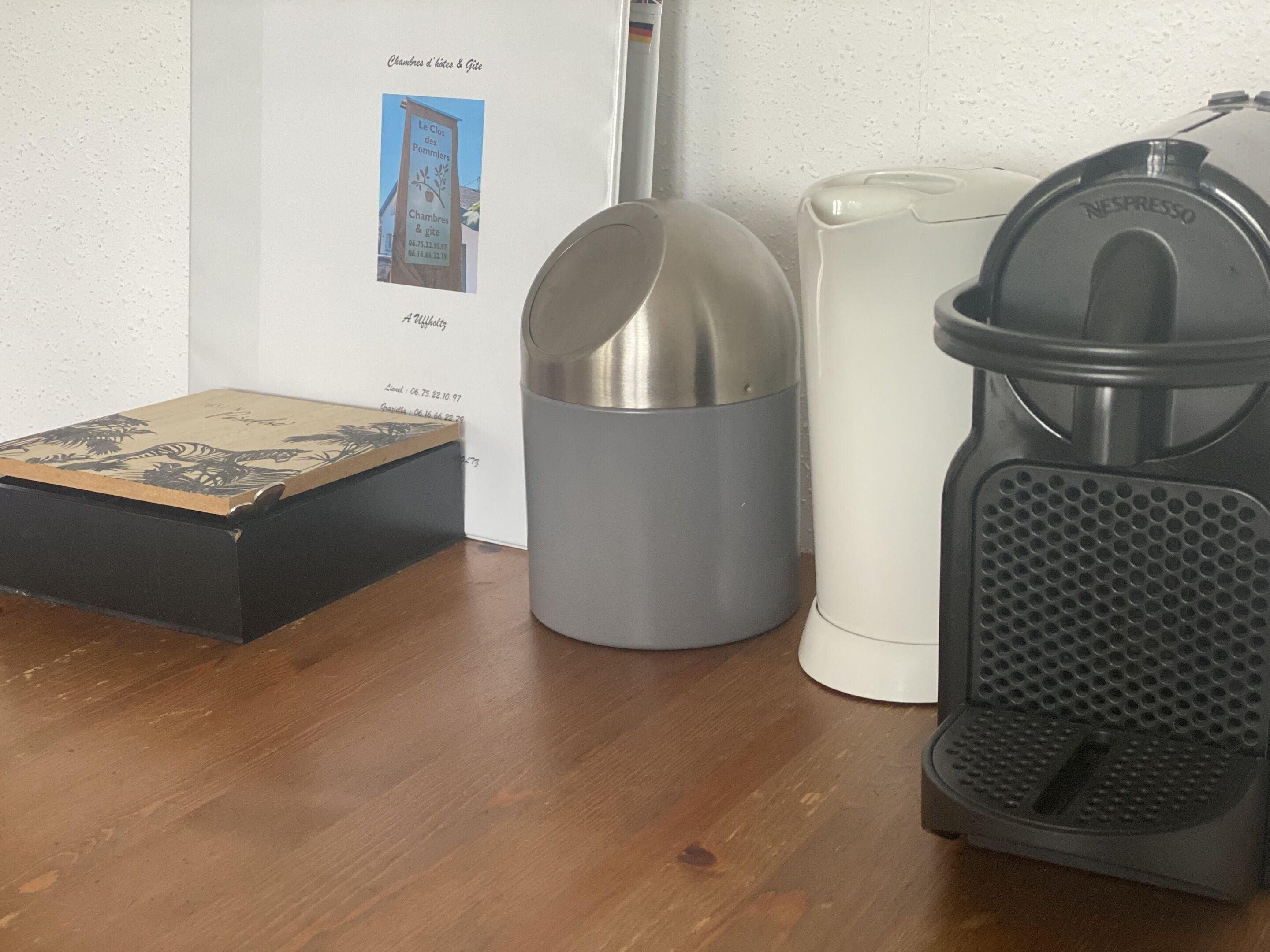 Un coin cuisine équipé d’une machine à café, d’une poubelle et d’une boîte posée sur le comptoir.