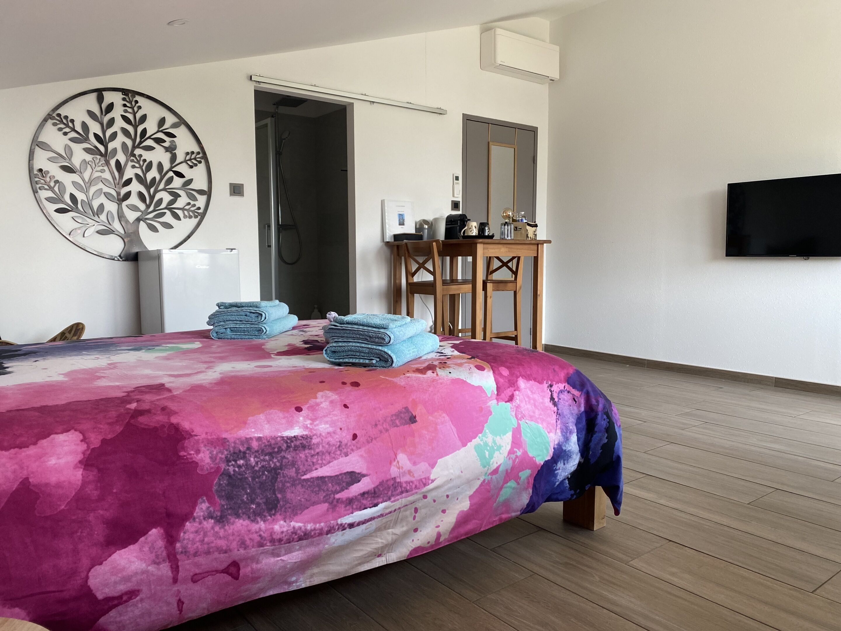 Un dormitorio moderno con una cama, un escritorio, una silla y un televisor montado en la pared.