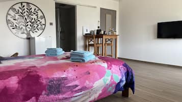 Un dormitorio moderno con una cama, un escritorio, una silla y un televisor montado en la pared.