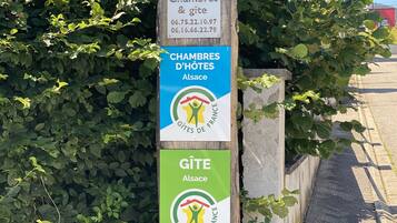 A wooden signpost with information about accommodations and a gîte in Alsace, France.