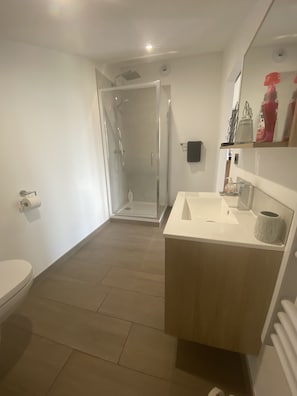 Ein modernes Badezimmer mit Toilette, Waschbecken und Duschbereich.