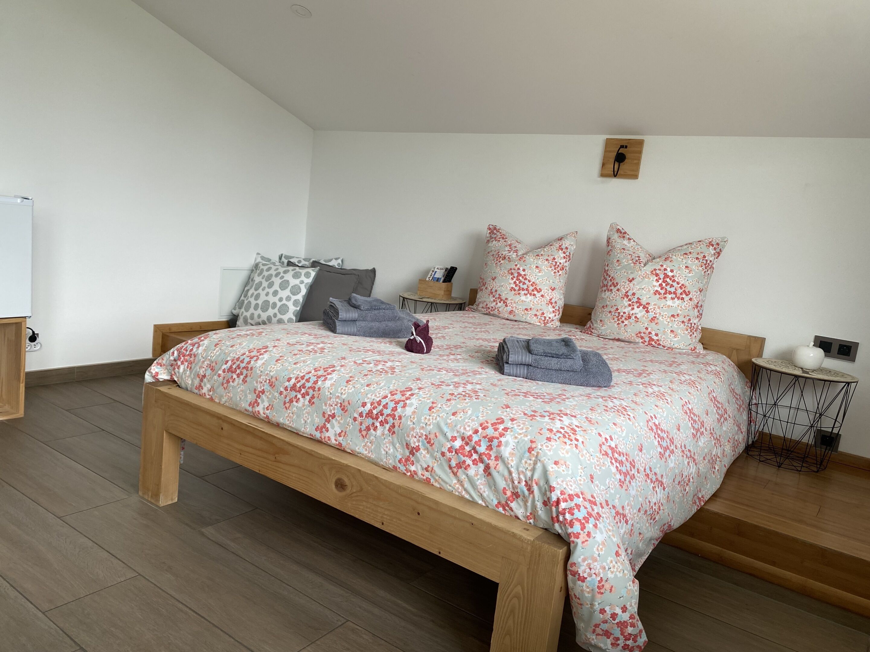 A bedroom with a wooden bed, floral bedding, and a small bedside table with a lamp.