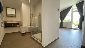Une salle de bain moderne avec une douche à parois de verre, un lavabo avec un miroir au-dessus et des toilettes.