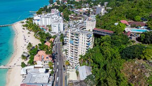 A coastal cityscape with a beachfront, multi-story buildings, and a road running through the center. - Ocean View Studio .... 5th Floor MBC Resort (Montego Bay)