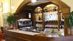 Una zona de bar con mostrador de madera, estantes con botellas y una cafetera.