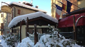 Entrada de un hotel con escalones cubiertos de nieve y un letrero que indica que es el Ristorante Hotel Cimone.