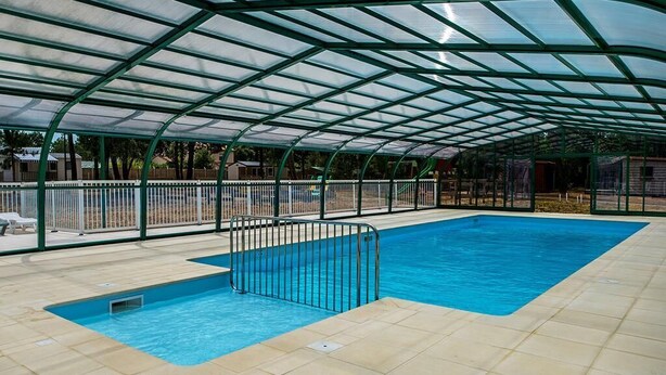 An indoor swimming pool with a glass ceiling and metal railings. - Camping le Chenal (Saint-Jean-de-Monts)