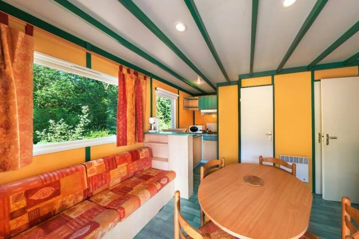 Una habitación acogedora con una mesa redonda de madera, un sofá y una ventana con cortinas.