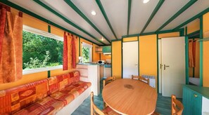 Une pièce chaleureuse avec une table ronde en bois, un canapé et une fenêtre avec des rideaux.