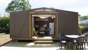 A compact, single-room structure with a kitchenette, a table, and chairs outside. - Camping le Chenal (Saint-Jean-de-Monts)