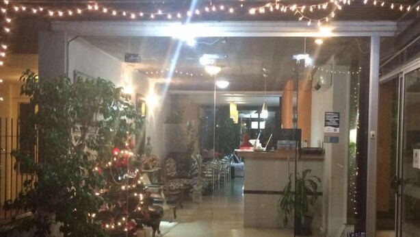 A hotel entrance with a reception desk, a Christmas tree, and a glass door.