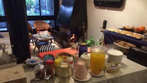 A breakfast buffet with various food items and beverages, a television mounted on the wall, and a window with a view of the outdoors.