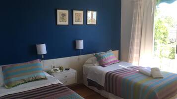 A room with two beds, a nightstand, and a window with curtains.
