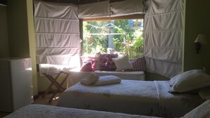 A cozy room with two beds, a small table, and a window with curtains.
