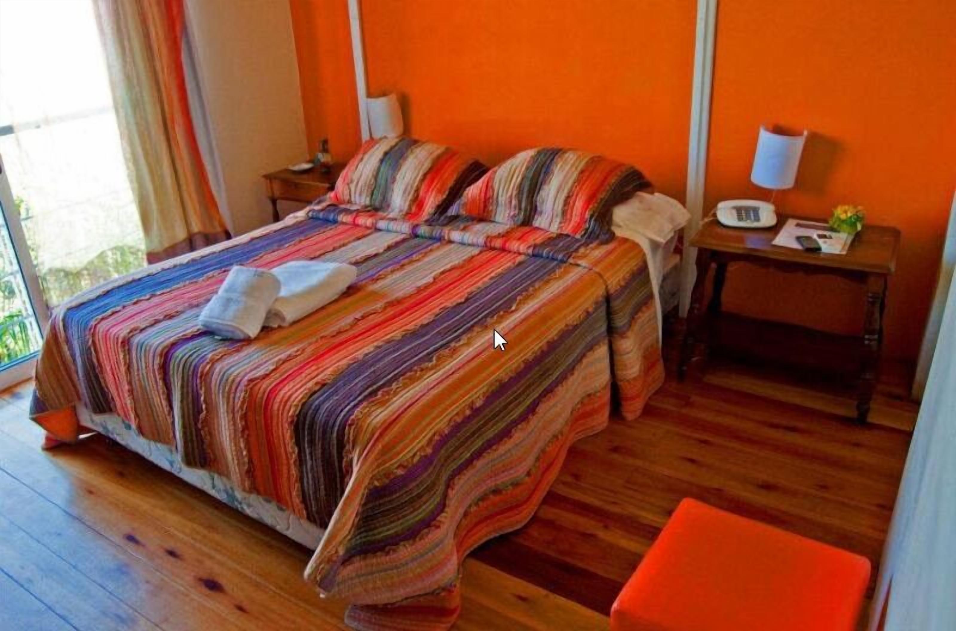 Una stanza con un letto, un comodino, una sedia e una finestra con tende.