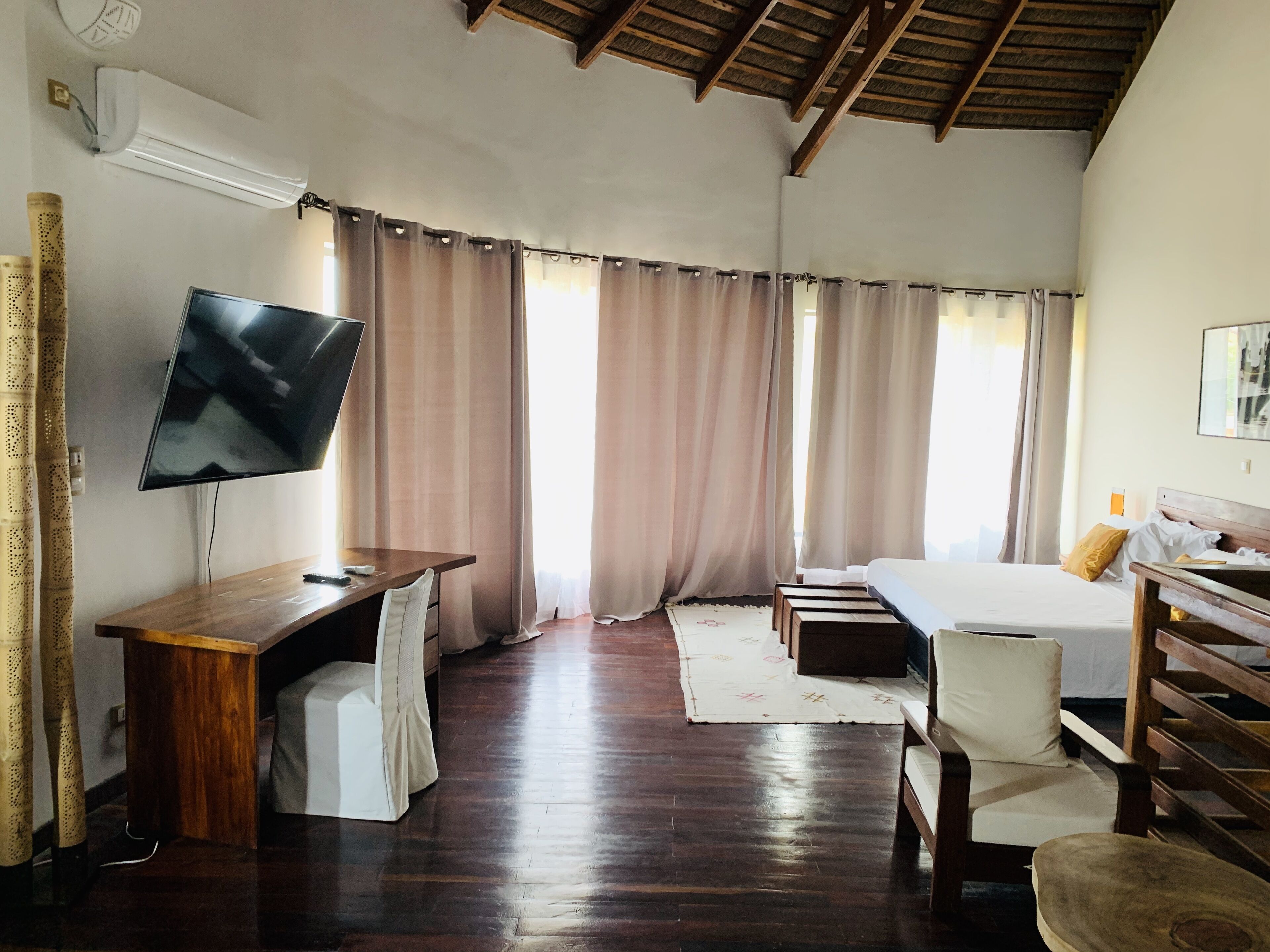 Una habitación de hotel con un escritorio de madera, un televisor de pantalla plana, una cama y una silla.