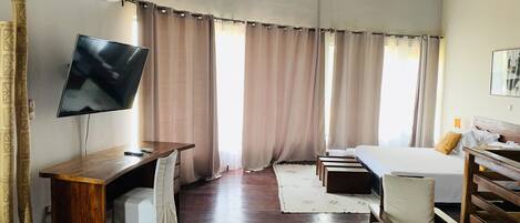 Una habitación de hotel con un escritorio de madera, un televisor de pantalla plana, una cama y una silla.