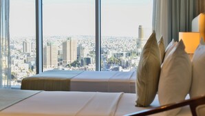 Une chambre d’hôtel dotée d’une grande fenêtre donnant sur la ville.