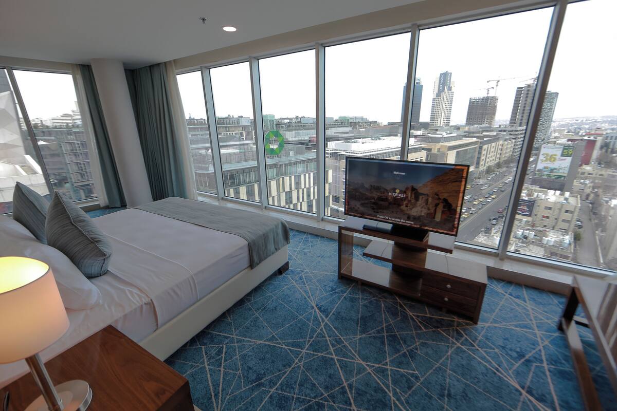 Une chambre d’hôtel avec un grand lit, une télévision et une vue sur le paysage urbain grâce à de grandes fenêtres.