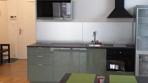 Una cocina compacta con un lavamanos, una estufa y una campana extractora negra.