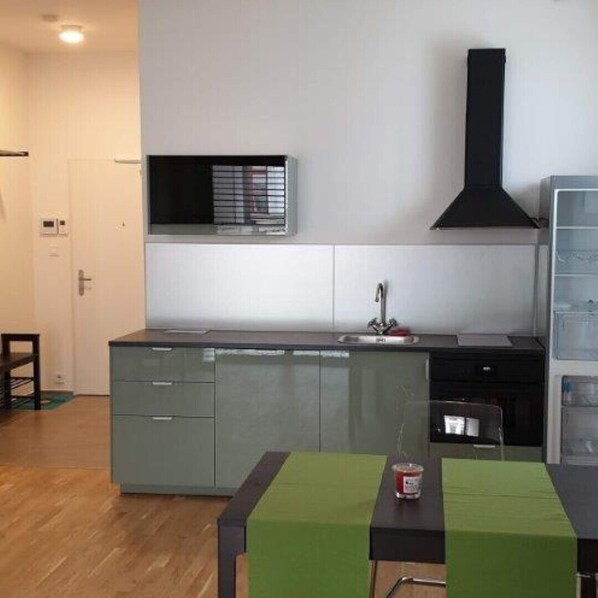 A compact kitchen with a sink, a stove, and a black range hood.