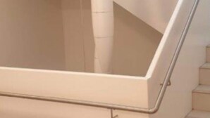 Una escalera con barandilla y paredes color beige.