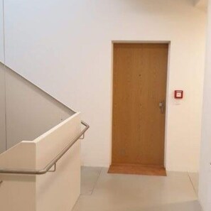 A hallway with a wooden door and a metal handrail.