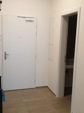 A room with a closed door, a small window, and a visible bathroom area.
