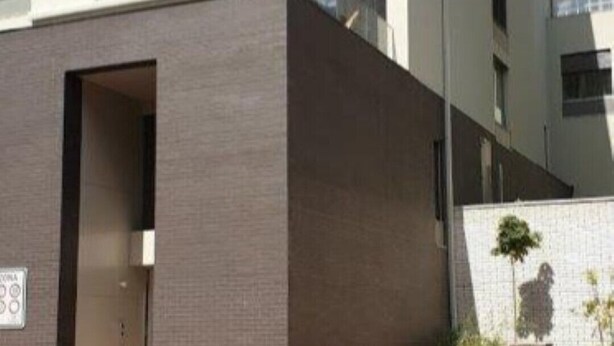 Un edificio moderno con fachada plana, varias ventanas y una entrada visible.