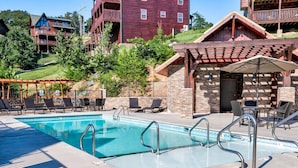 A pool area with lounge chairs and a stone building.