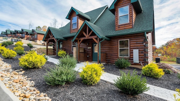 A log cabin-style hotel with multiple rooms, a covered porch, and landscaped gardens.