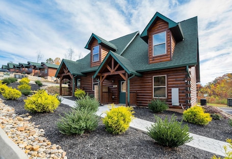 A log cabin-style hotel with multiple rooms, a covered porch, and landscaped gardens.
