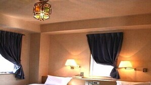 A hotel room with two beds, a nightstand, a lamp, and a window with curtains. - Matsue City Hotel  - Annex (Matsue)