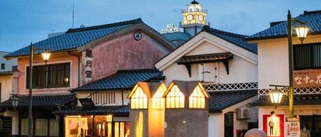 A traditional Japanese building with a clock tower, a stone lantern, and a signboard.