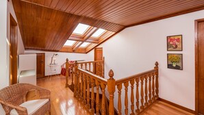 A spacious loft with a wooden ceiling, a wooden staircase, and a skylight. - Fonte Branca Guest House (Braga)