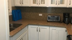 A kitchen with white cabinets, a granite countertop, a toaster, and a coffee maker. - Ocean View Condo....IN NEGRIL (NEGRIL)