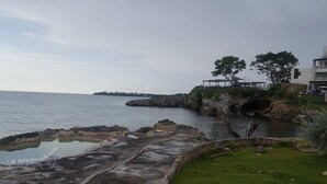 A coastal area with a rocky shoreline, a small pool, and a gazebo overlooking the sea. - Ocean View Condo....IN NEGRIL (NEGRIL)