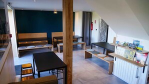 Un intérieur moderne avec un mélange de meubles en bois et de meubles noirs, notamment un canapé, une table et des bancs. On y trouve un petit comptoir d'accueil avec une enseigne et quelques objets.